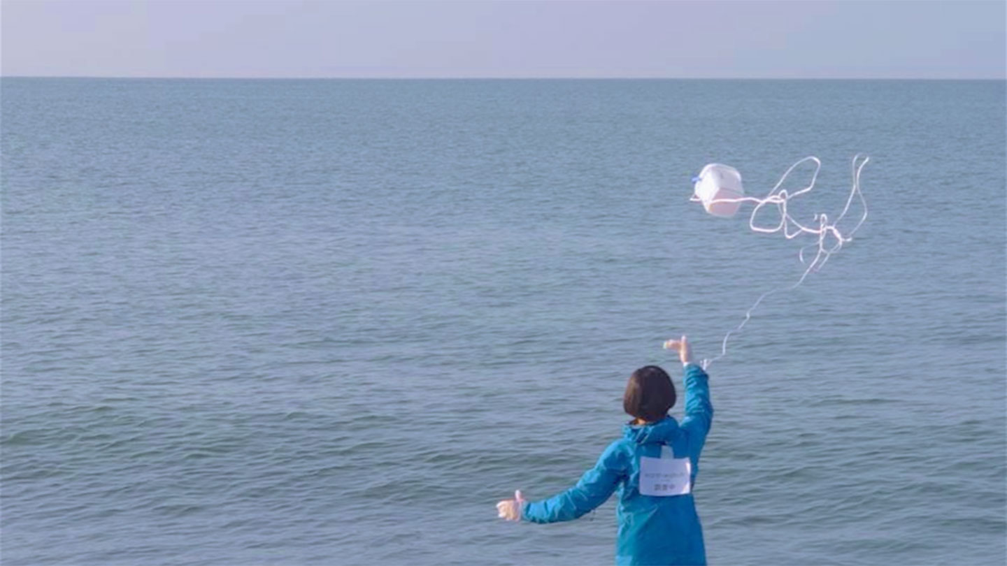 ボランティアがバケツを投げて海水を採取している様子