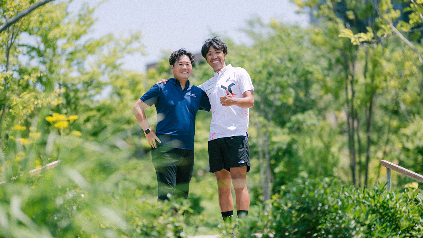 笑顔で肩を組む細田雄一さんと坂田洋治さん