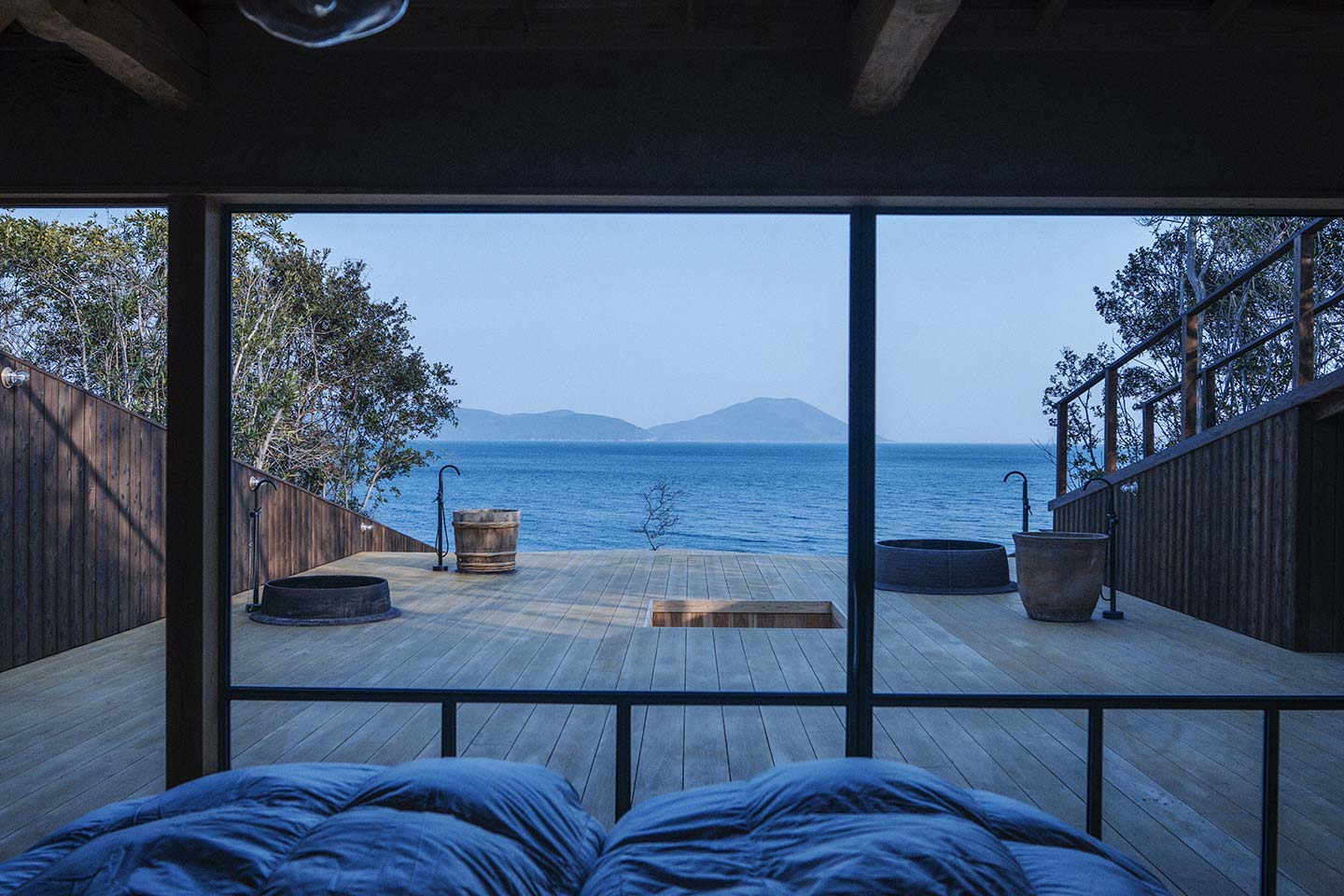 メディテーションサウナヴィラ「tou」の窓から見える広比としたテラスと、その先に見える海と山の風景