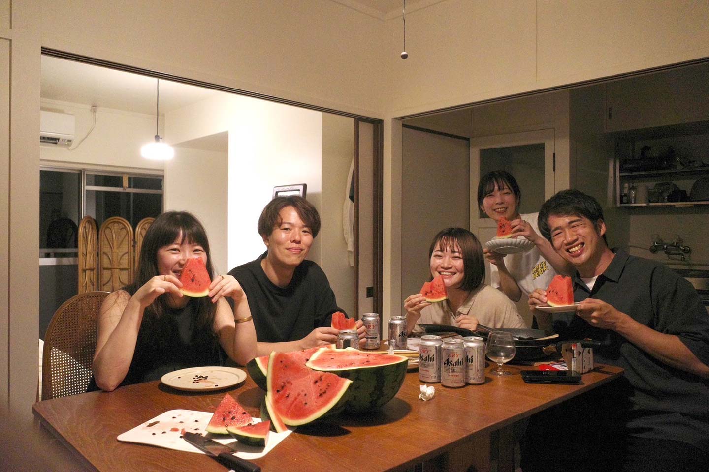 アパートの室内で、住民の5人がスイカを食べている様子