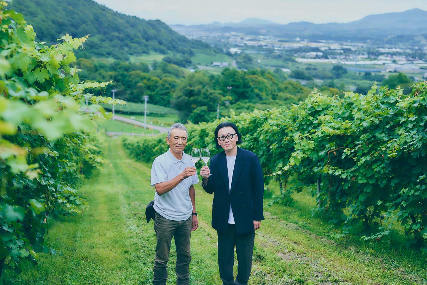 NIKI Hills Wineryのブドウ畑で乾杯するひぐち君と総支配人の舟津さん