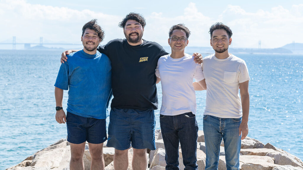 瀬戸内海をバックにデニム兄弟とオリーヴ兄弟が肩を組む様子