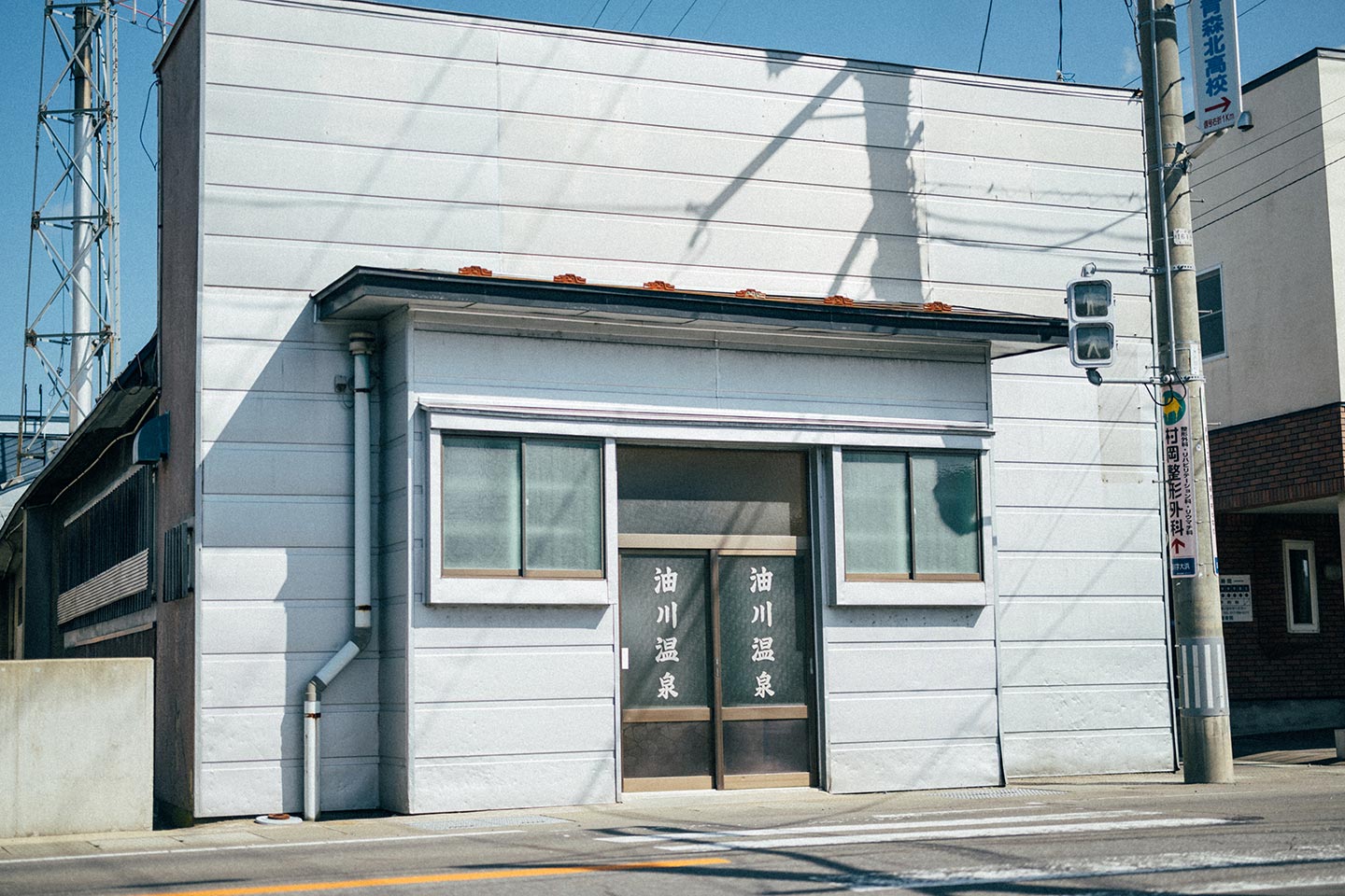 青森県青森市にある油川温泉の外観。引き違いの扉のガラスに、縦書きで「油川温泉」と白い文字が書かれている