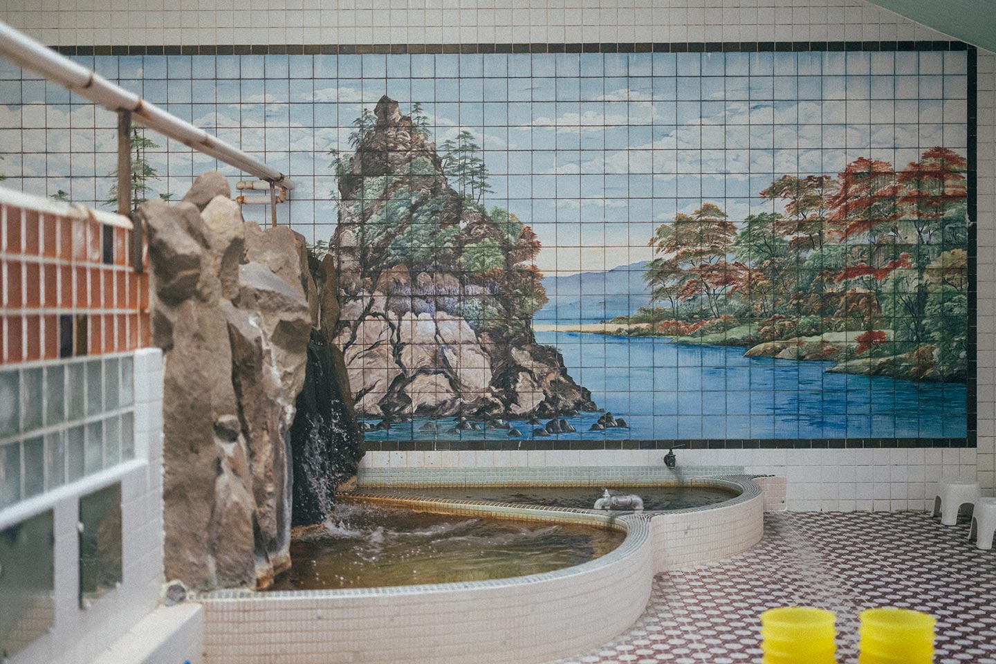 青森市油川温泉の浴室。浴槽が二つあり、突き当りの壁一面に、海に浮かぶ小島のような風景が描かれている