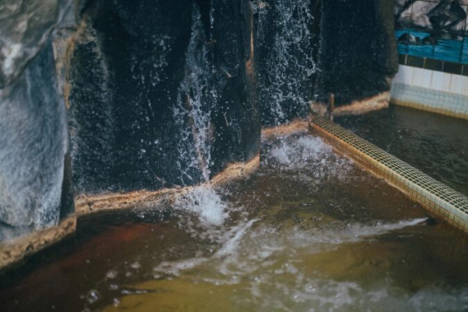 岩肌を伝って流れ込む温泉のお湯は褐色に濁っている