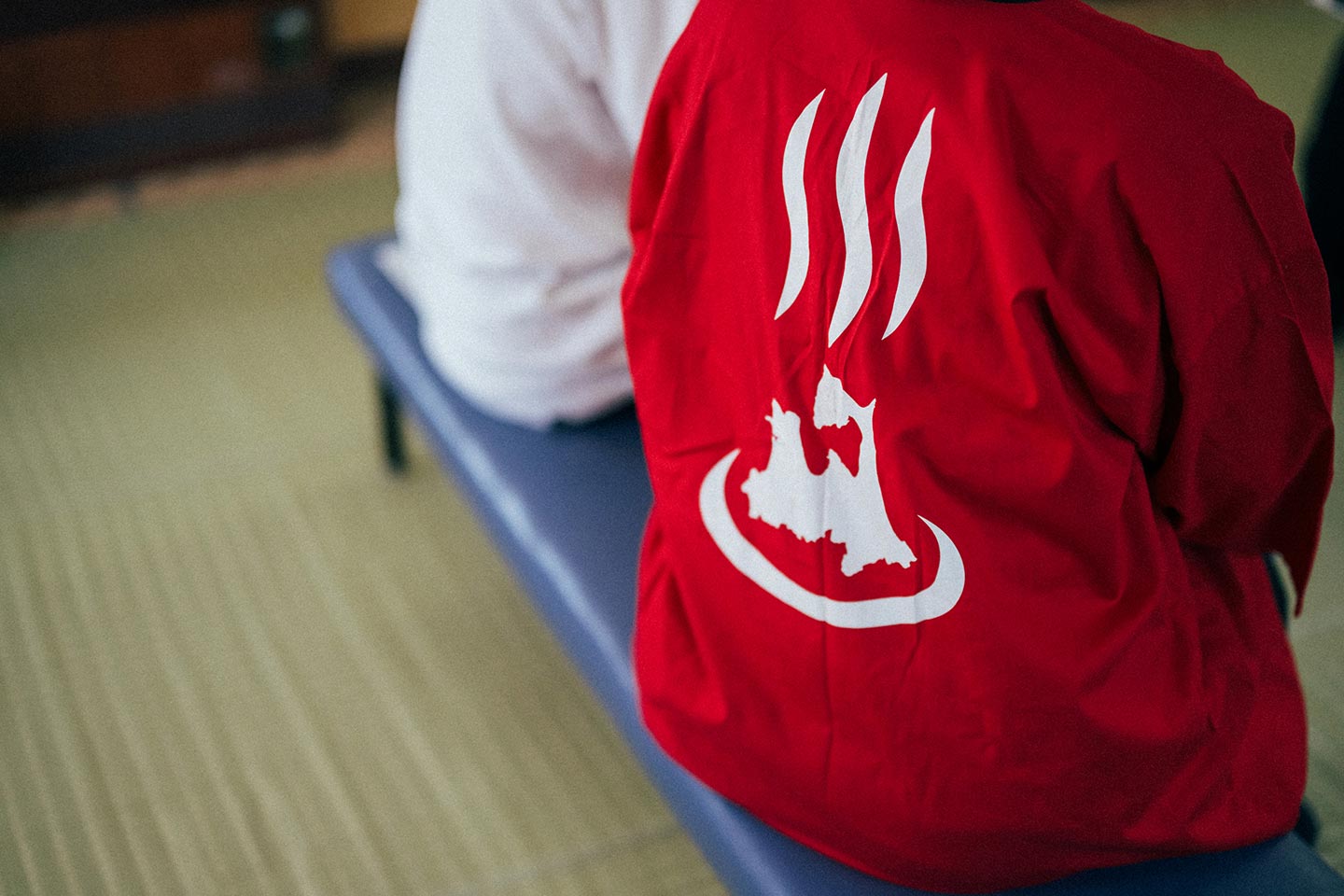 沓掛さんが来ている赤い法被の背中には、青森県の形と温泉マークを掛け合わせた「青森の湯っこ協会」のシンボルが描かれている