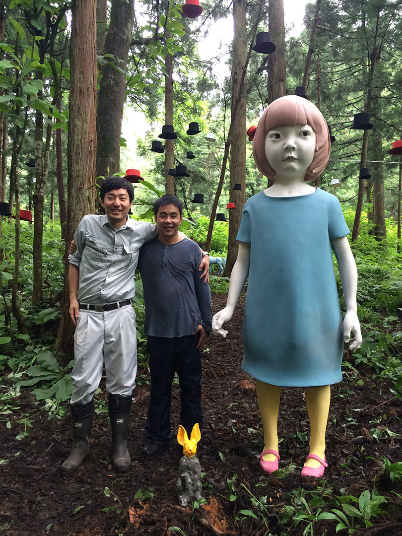 井比さんと作家さんがアート作品のそばで肩を組んで写っている