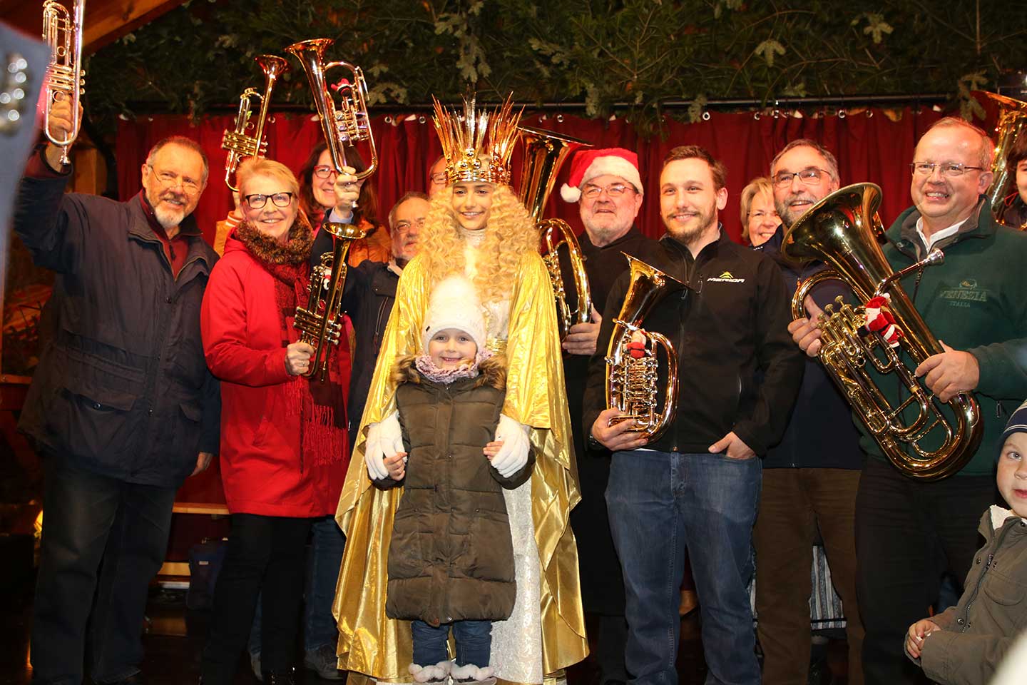 中央に、クリスマスマーケットに登場したニュルンベルクのクリストキント（クリスマスの天使とされている）。大きな王冠をかぶり、金色の長いマントを着ている。管楽器を持ったひとたちに囲まれている