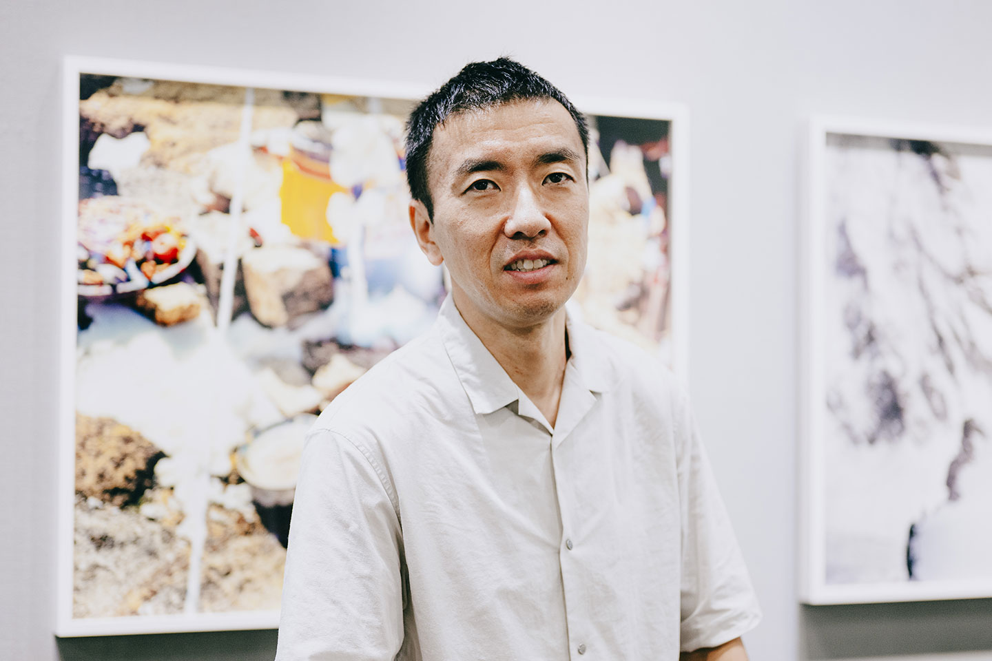 写真作品の前に立って微笑んでいる石川直樹さん