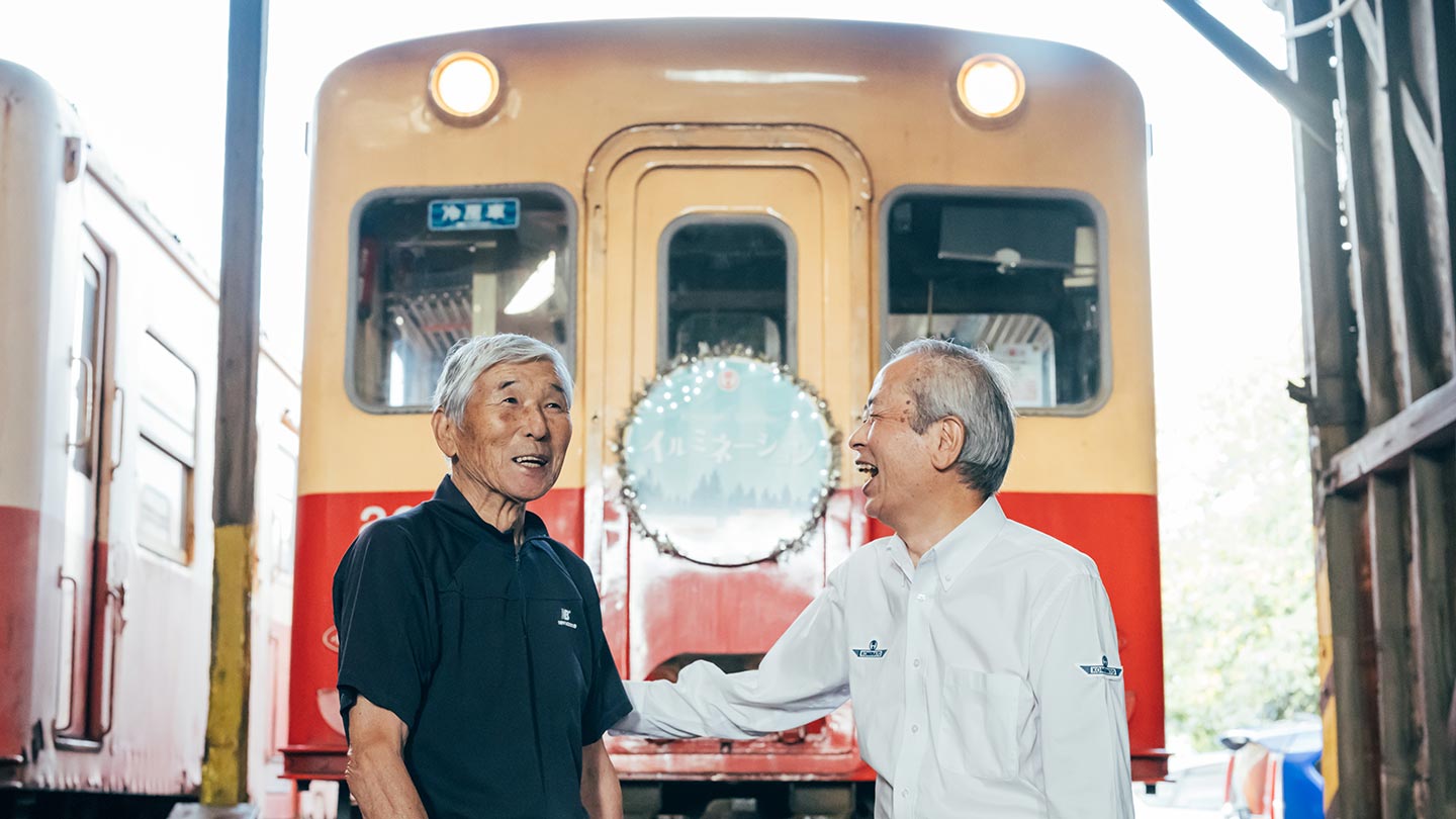 イルミネーションの看板がついた車両の前で笑い合う松本さんと池田さん