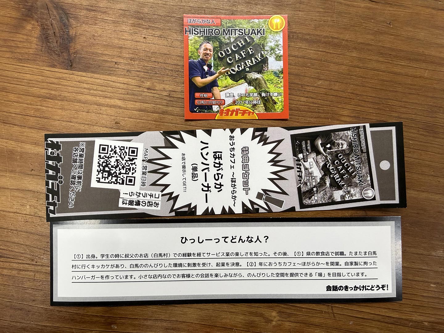 「おうちcafe ほがらか」店主の日城光朗さんの顔写真が写った村民カードと、プロフィールが記載された特典チケット」