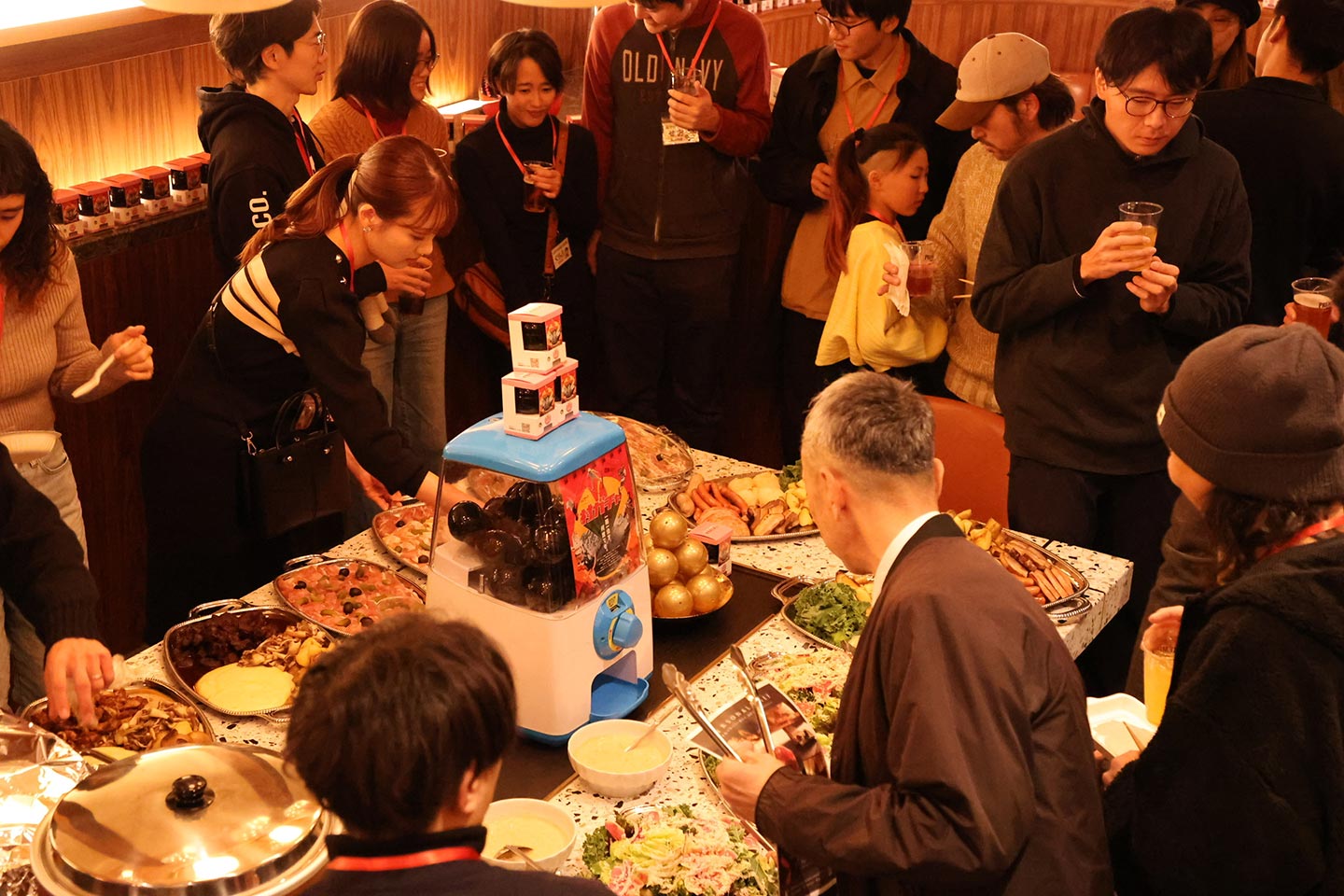 「村ガチャ感謝祭」で、村ガチャと料理が並べられたテーブルを囲む参加者たち