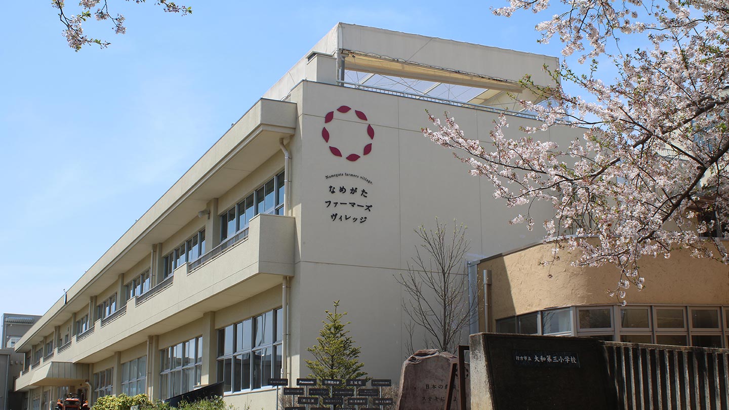 建物の外観は小学校のままで、外壁にらぽっぽなめがたファーマーズヴィレッジのロゴが設置されている。門には学校名が残されている