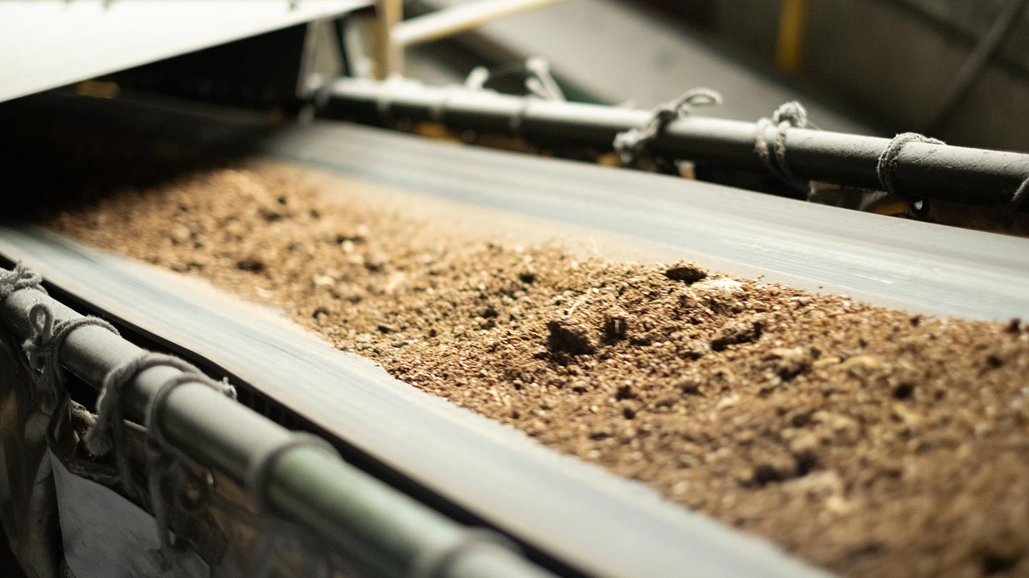 乾燥工程を経てベルトコンベアで運ばれる鶏ふん