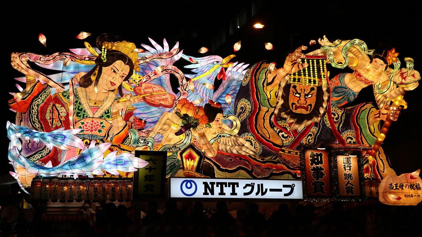 闇夜に光っている、男女や鳥をモチーフにつくられた巨大なねぶた