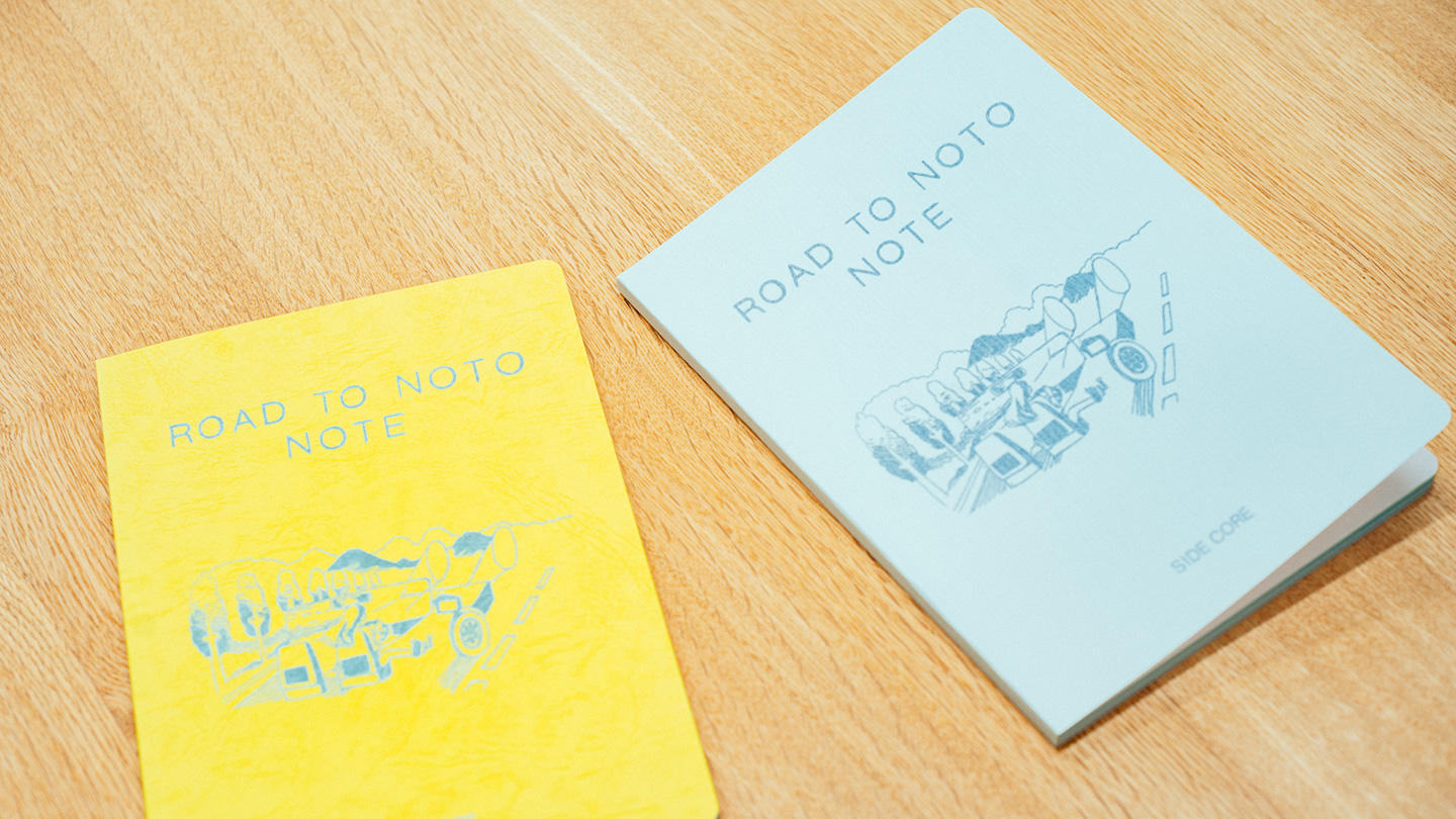 左から、黄色いノートと青色のノートが置いてあり、どちらの表紙にも『ROAD TO NOTO NOTE』というテキストとイラストが描かれている