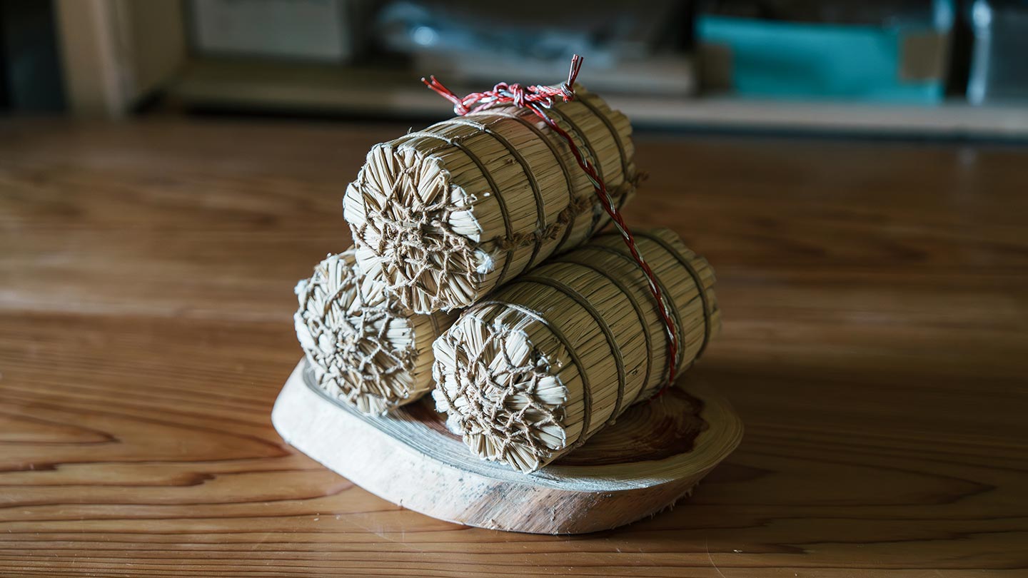 わら細工のミニチュア米俵。下に2俵、その上に1俵が乗っている