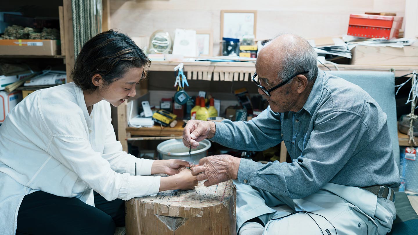 作業台をはさんで左に智香さん、右に清さんが向き合い、協力してわら細工をつくっている