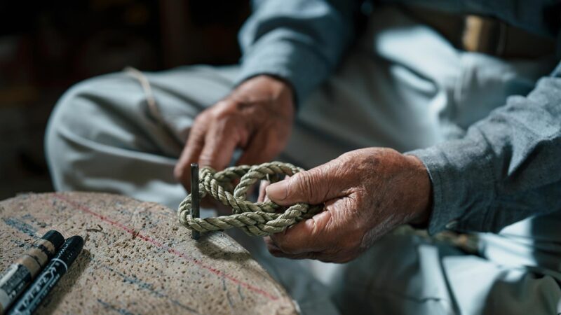 清さんがしめ縄をつくる様子。わらをなってつくった縄を結び、しめ縄をかたちづくる