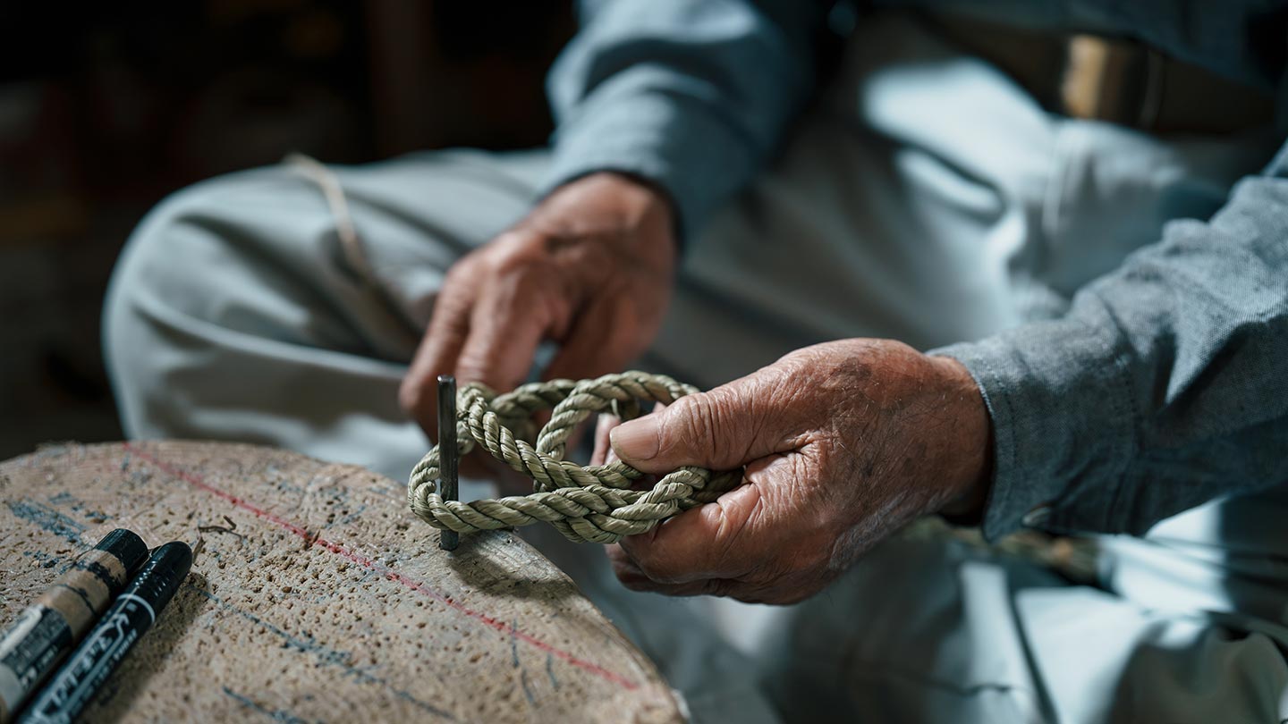 清さんがしめ縄をつくる様子。わらをなってつくった縄を結び、しめ縄をかたちづくる