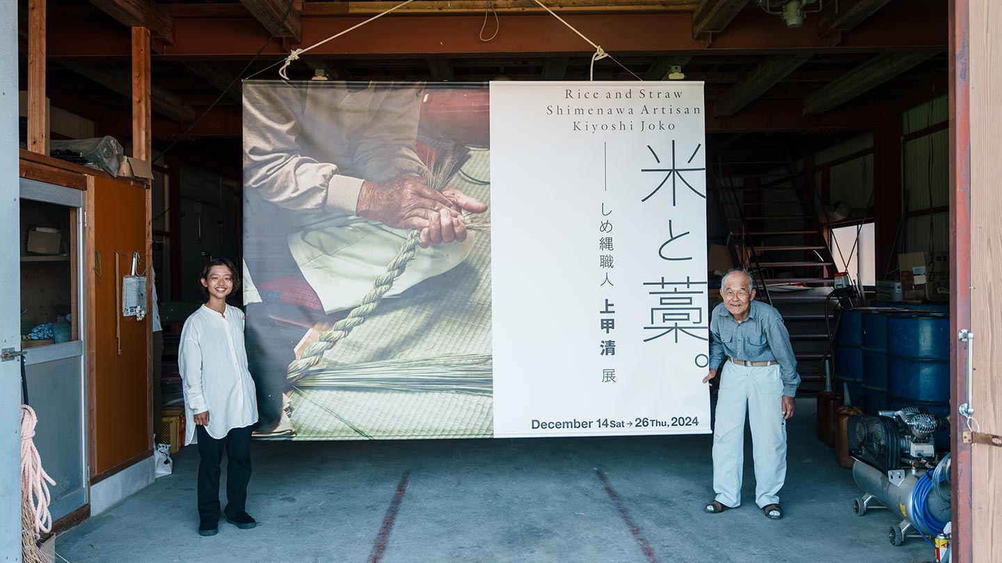 展示で使用した、2メートルほどある垂れ幕のわきに清さんと智香さんが立っている