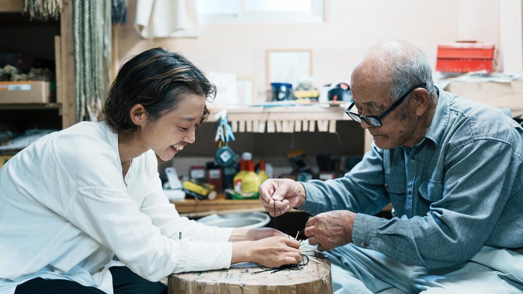 祖父と孫娘で協力し合い、工芸品をつくっている様子