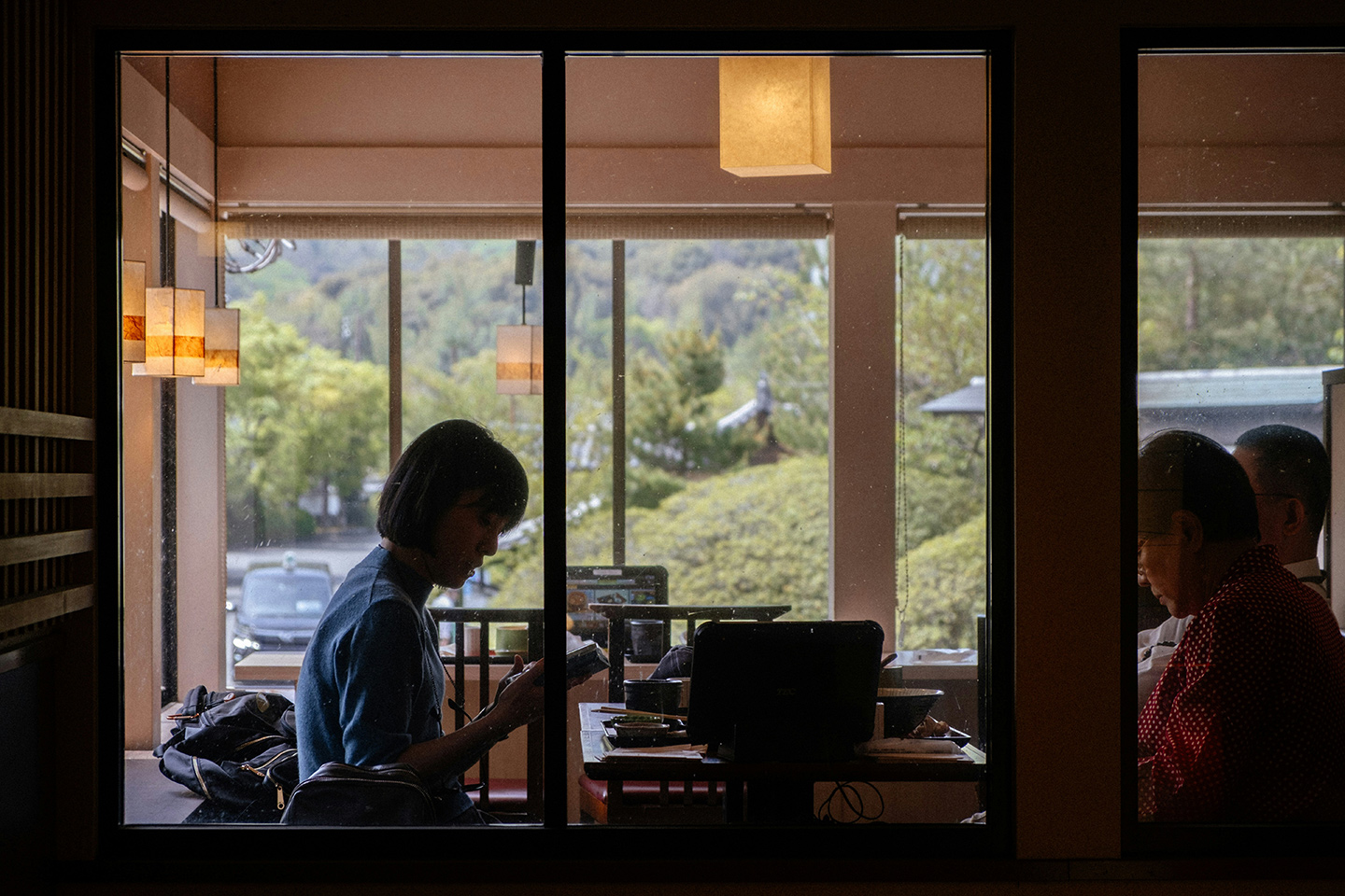 背景に山が見える部屋の中で、本を読んだり作業したりしている人たち