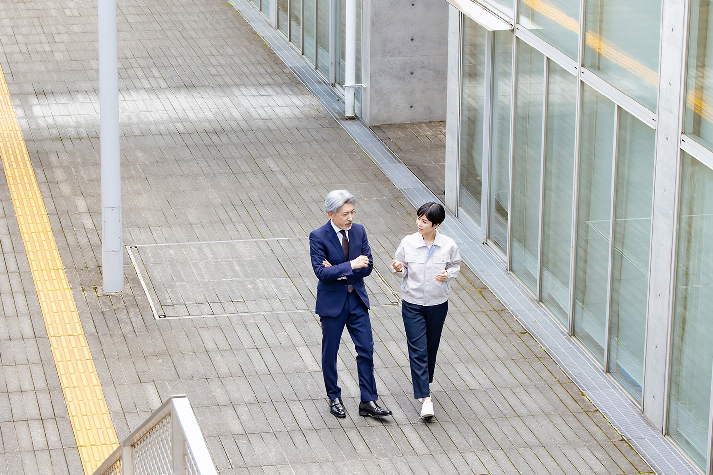 オフィスビル前の道で話をする、自治体職員男女