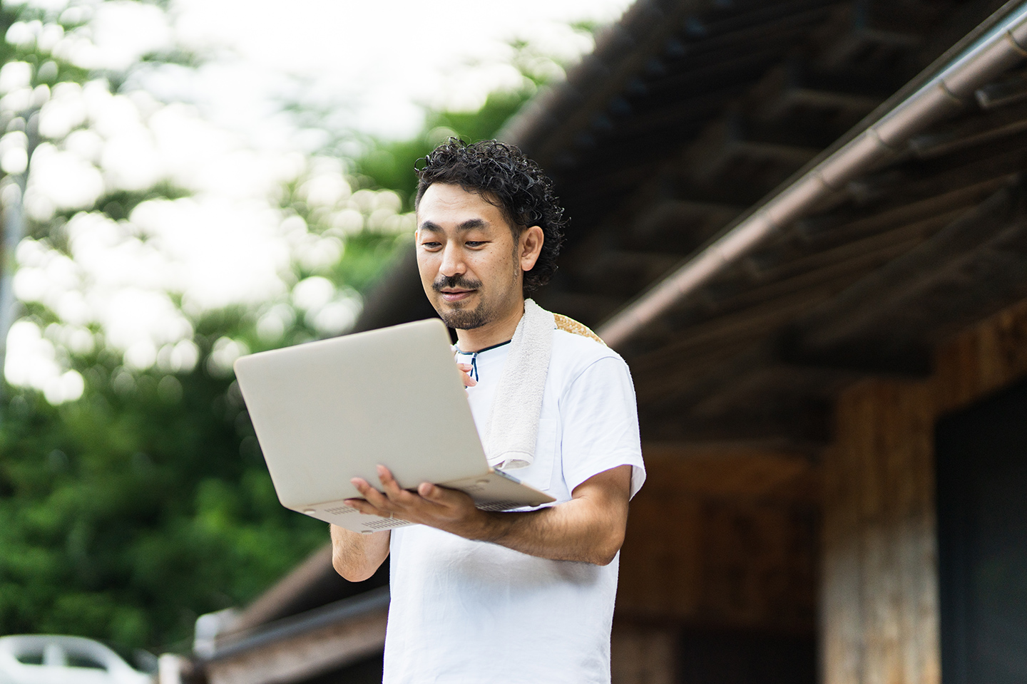 古民家の前でパソコンを操作する男性