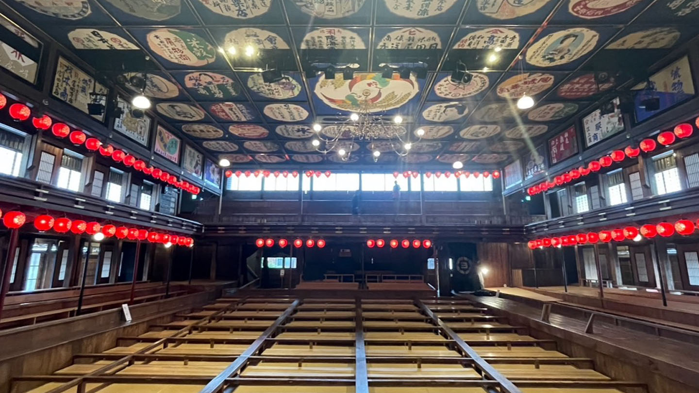 舞台から客席側を眺めた八千代座の内観。天井には色鮮やかな広告絵図が並んでいる