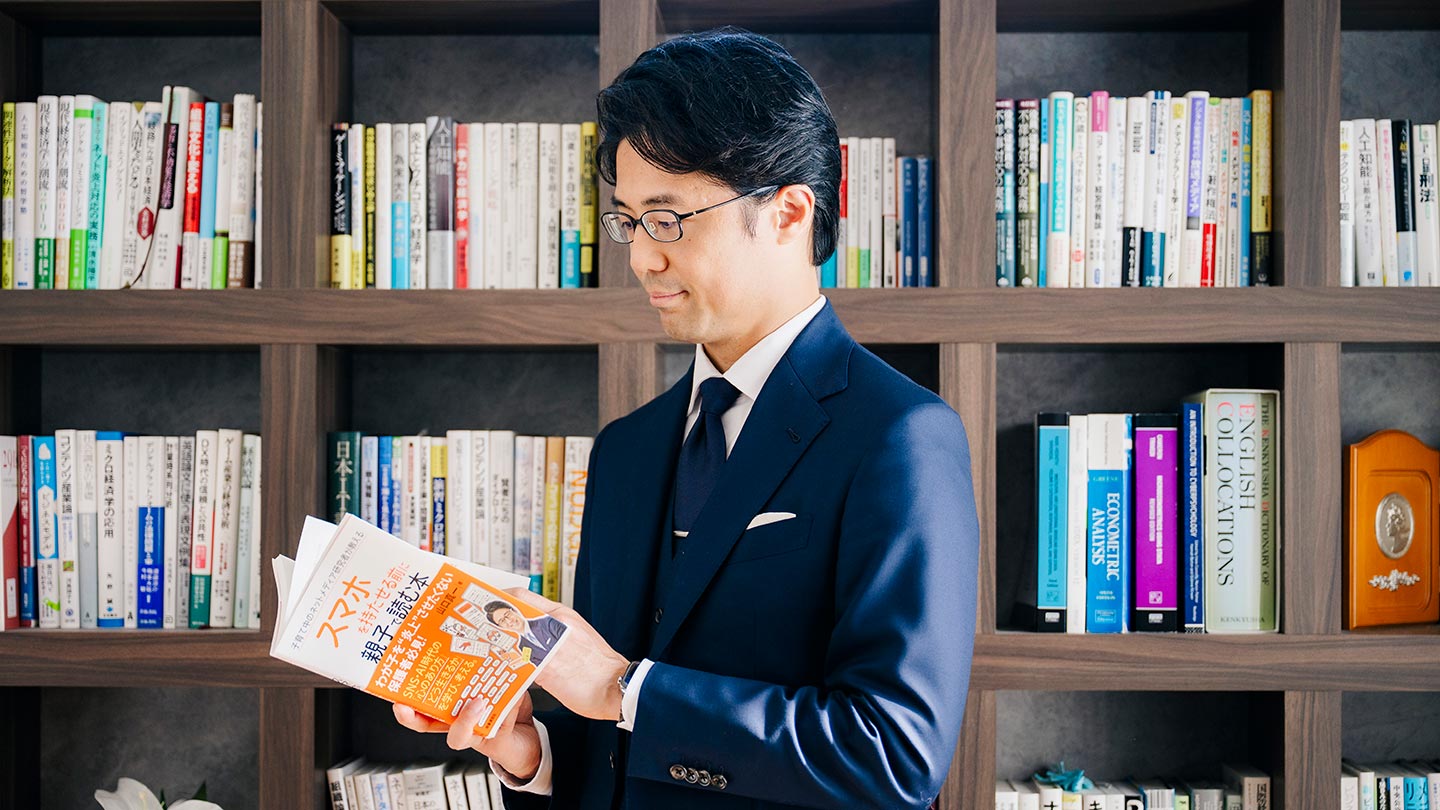 著書『スマホを持たせる前に親子で読む本』を手に取る山口さん