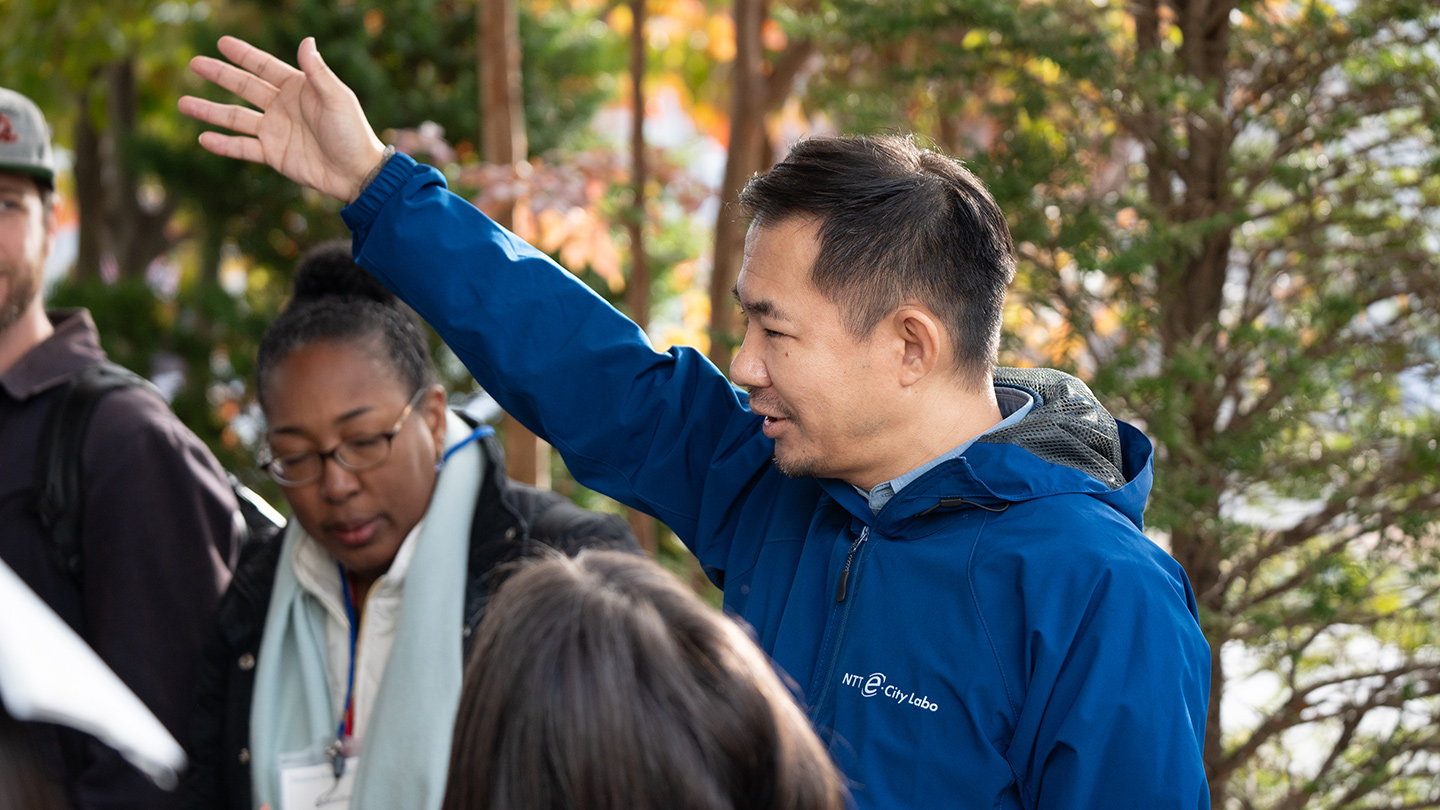 森を背景に、防災訓練の説明をしている佐野さん