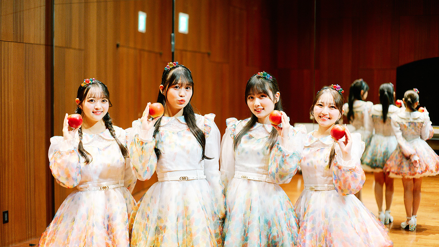 それぞれりんごを手に持って微笑む、りんご娘メンバー4人