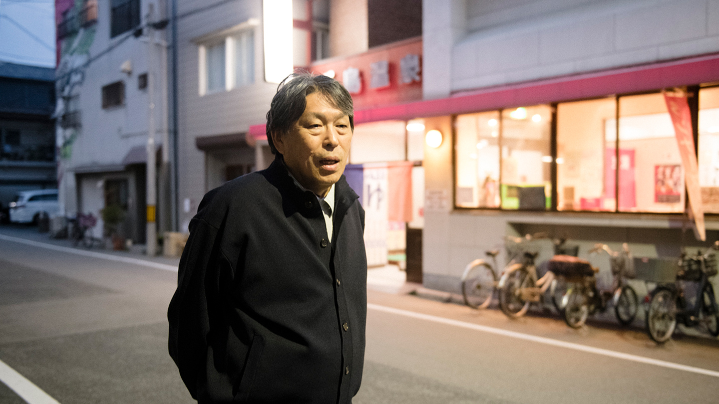 千鳥温泉の前に立ちお話している松本さん