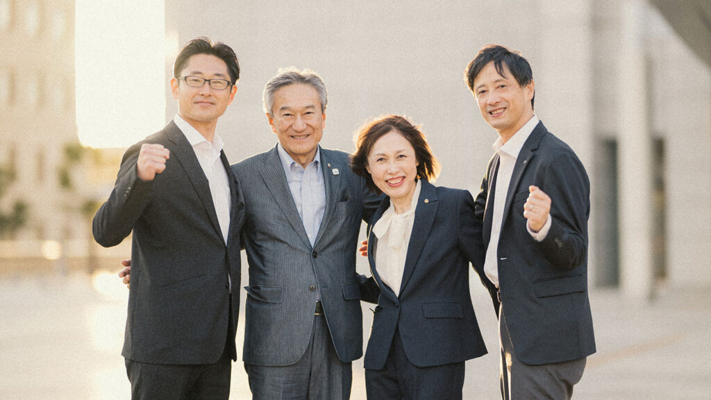 取材を受けた4人が肩を組んで立っているポートレート