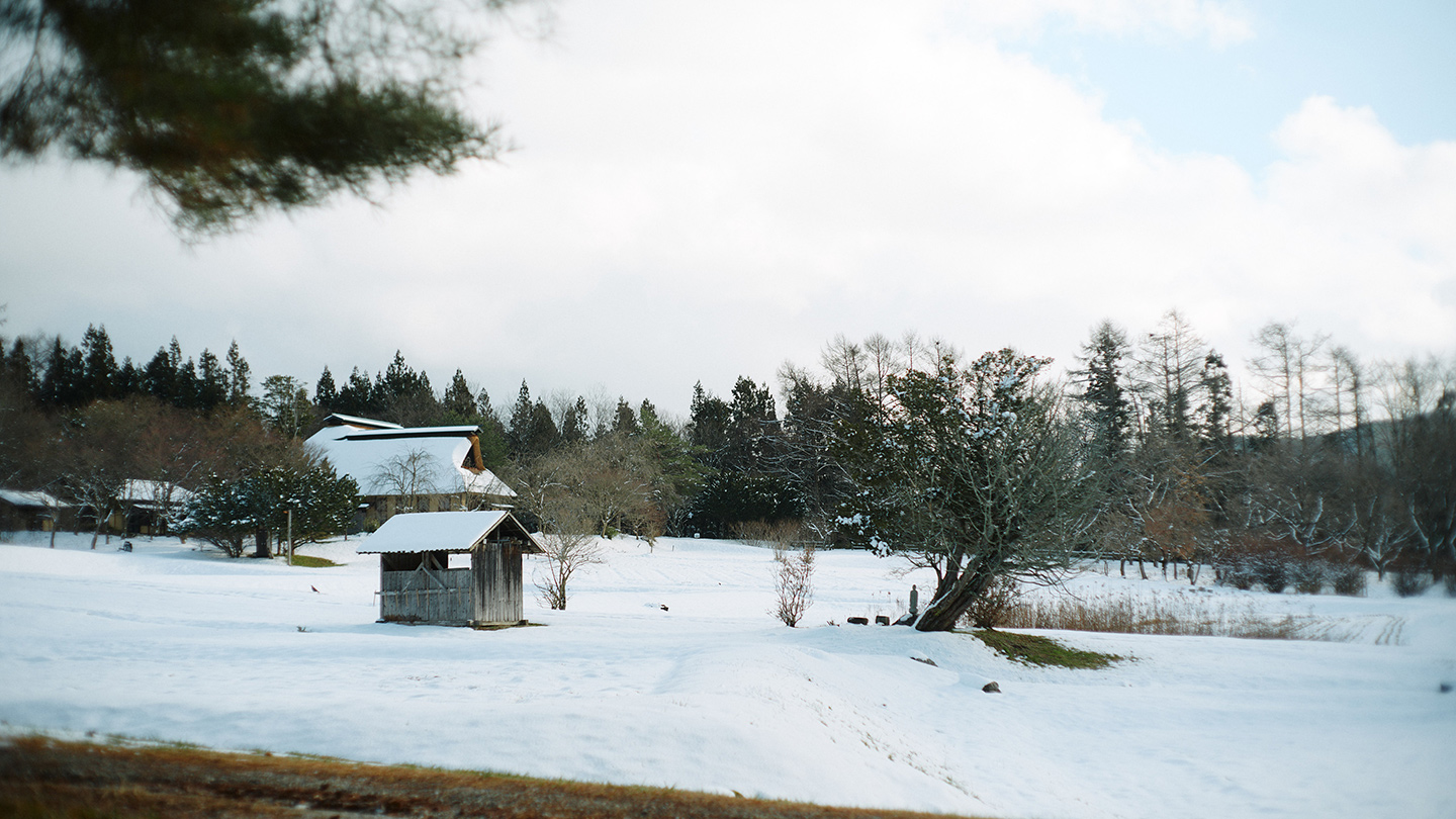 山林に囲まれた遠野の雪景色。昔ながらの木造建築の家が点在している