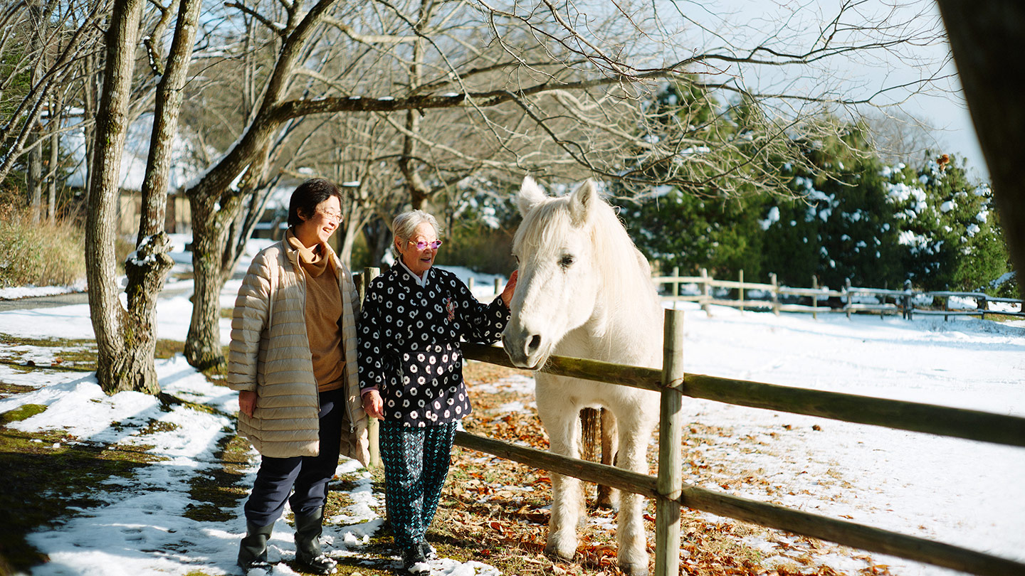 白馬と触れ合う細越澤さんと前川さん