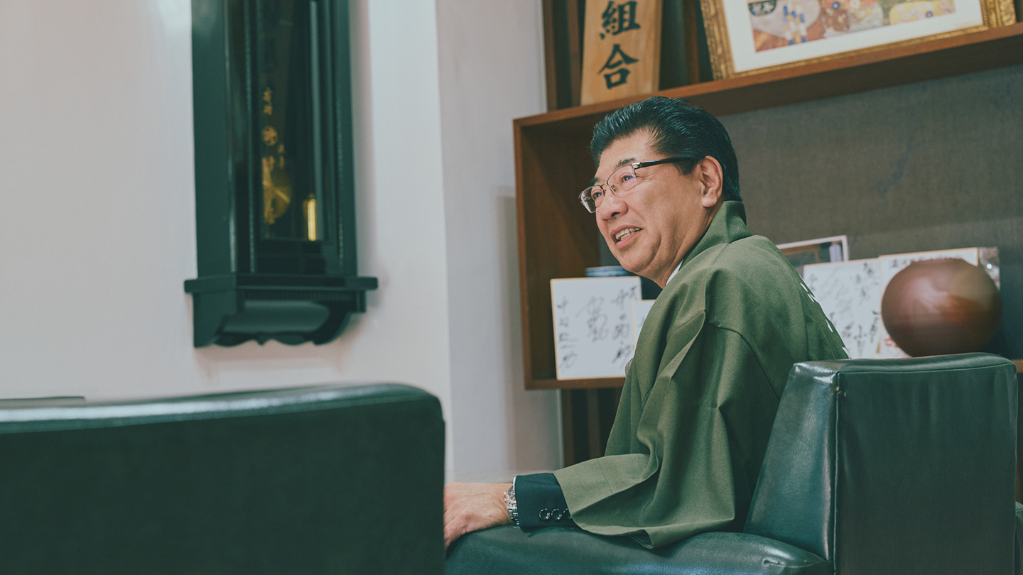 椅子に座って話をする、湯河原温泉観光協会会長の石田浩二さん