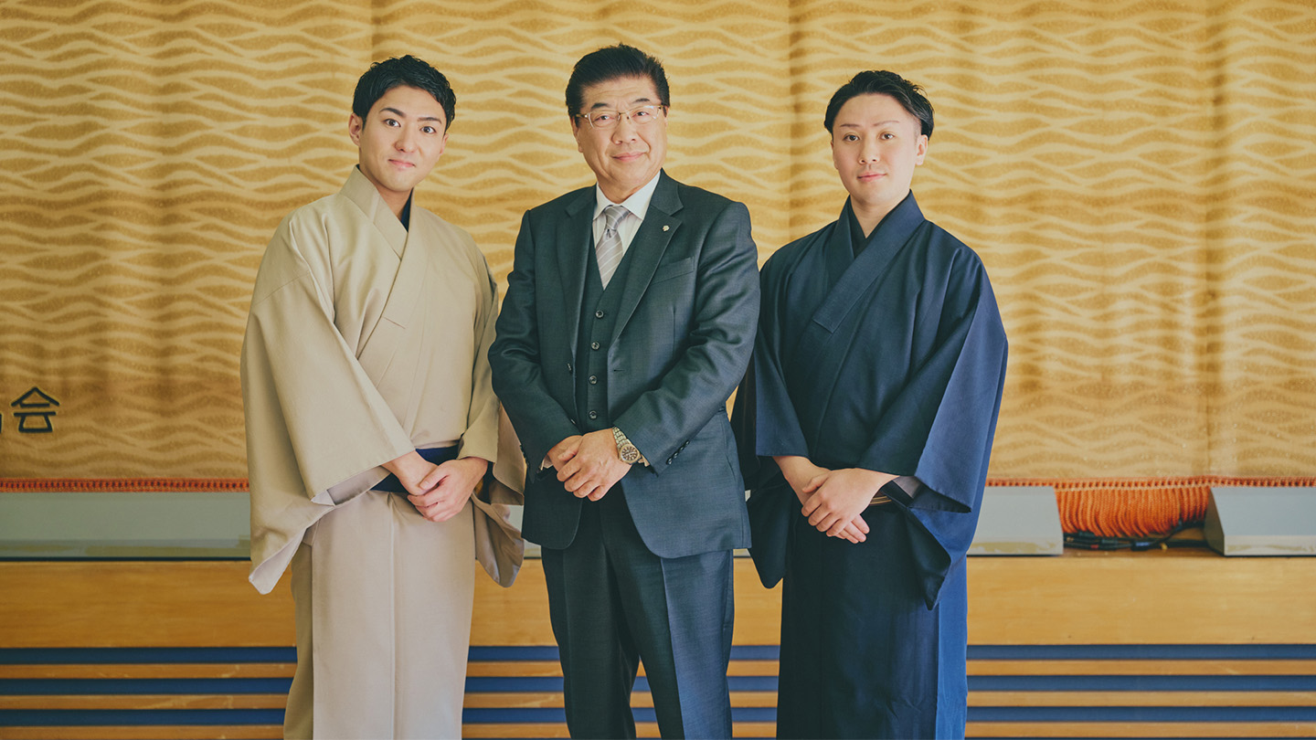 湯河原見番の緞帳の前に立つ、中村橋之助さん、石田浩二さん、藤間直三さん