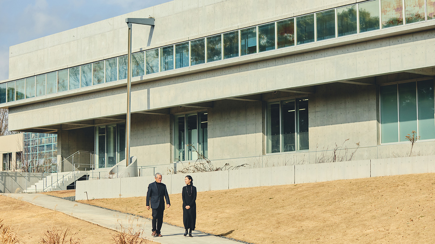 千葉大学構内の建物の前の坂を歩く賀来さんと秋田さん