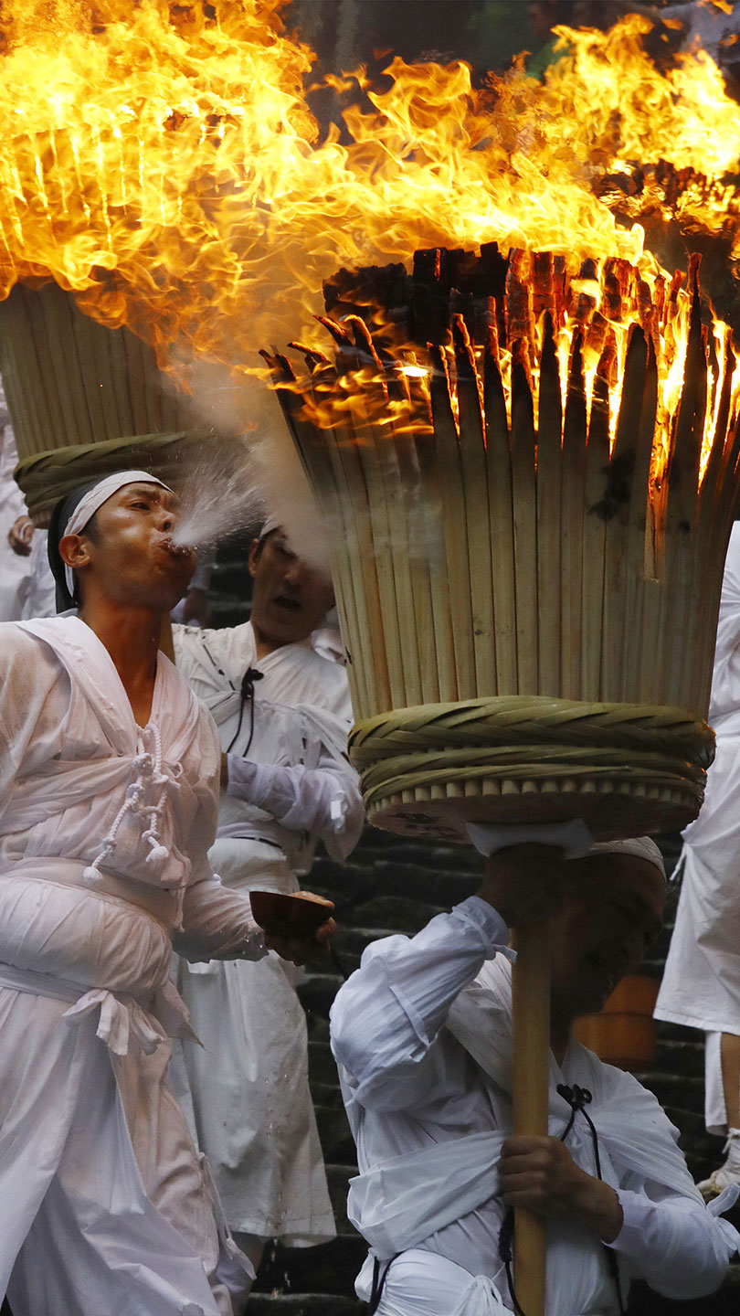 松明に向かって水を吹きかける男