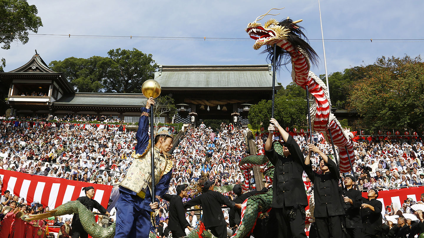 中国服を着た人々が大きな龍を掲げている。金色の球がついた棒を掲げる男性が手前にいる