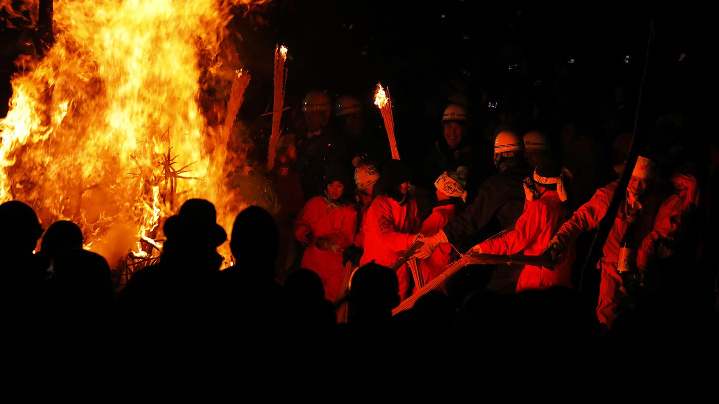 暗闇のなか、大きな炎が上がっている。それらを見る人々