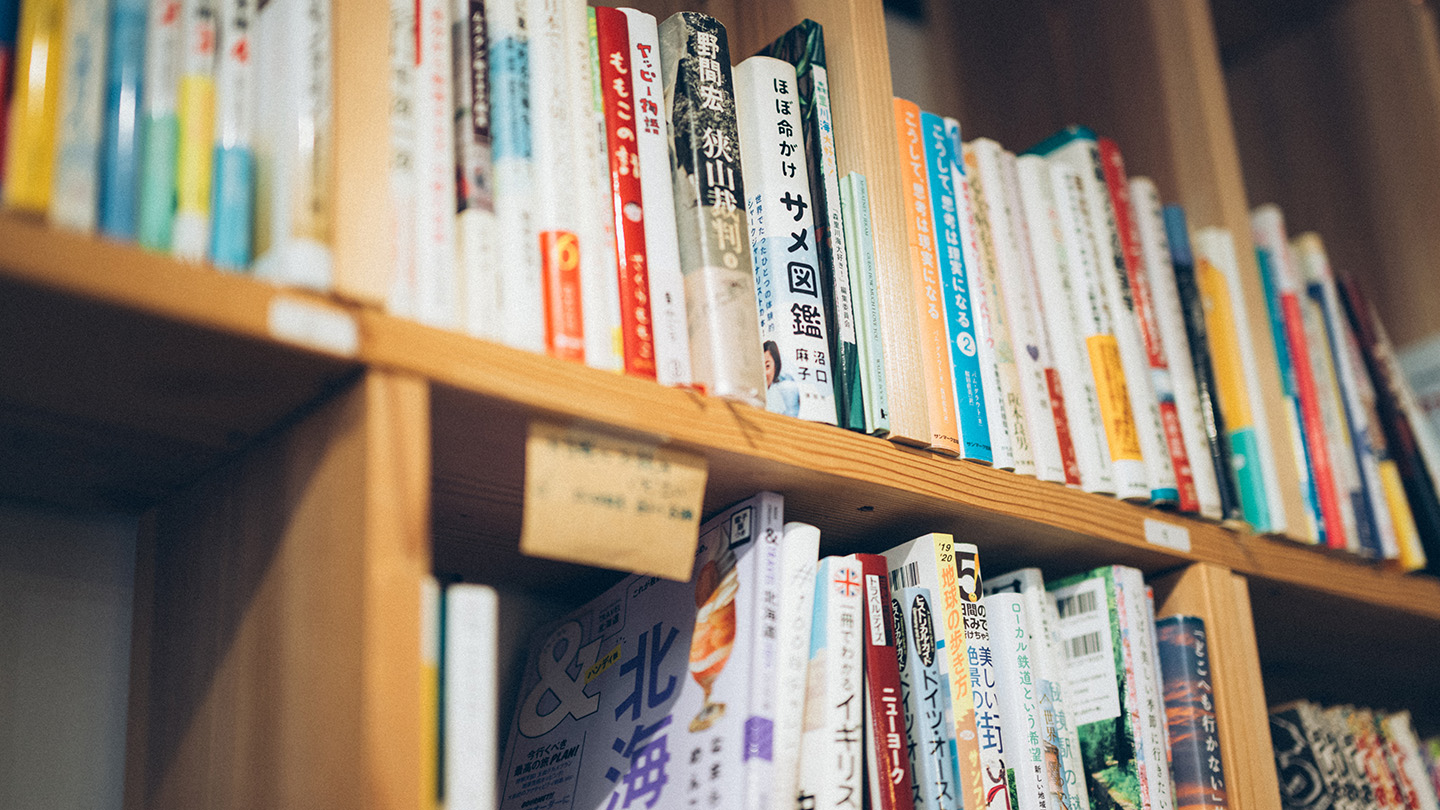 木製の本棚にずらりと並んだ本の背表紙。手書きの付箋メモも貼られている