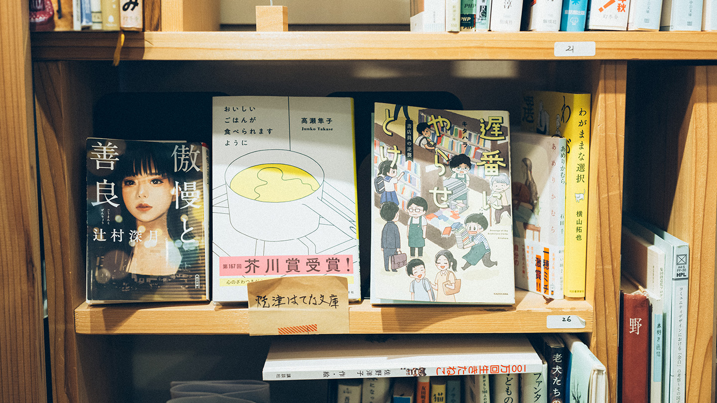 木製の本棚の一段に、表紙が見えるかたちで並べられた数冊の本のアップ