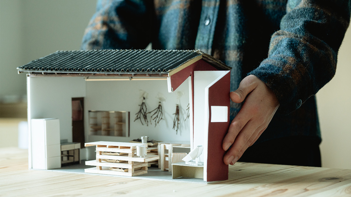 小さな家の模型と、それに添えられた男性の手