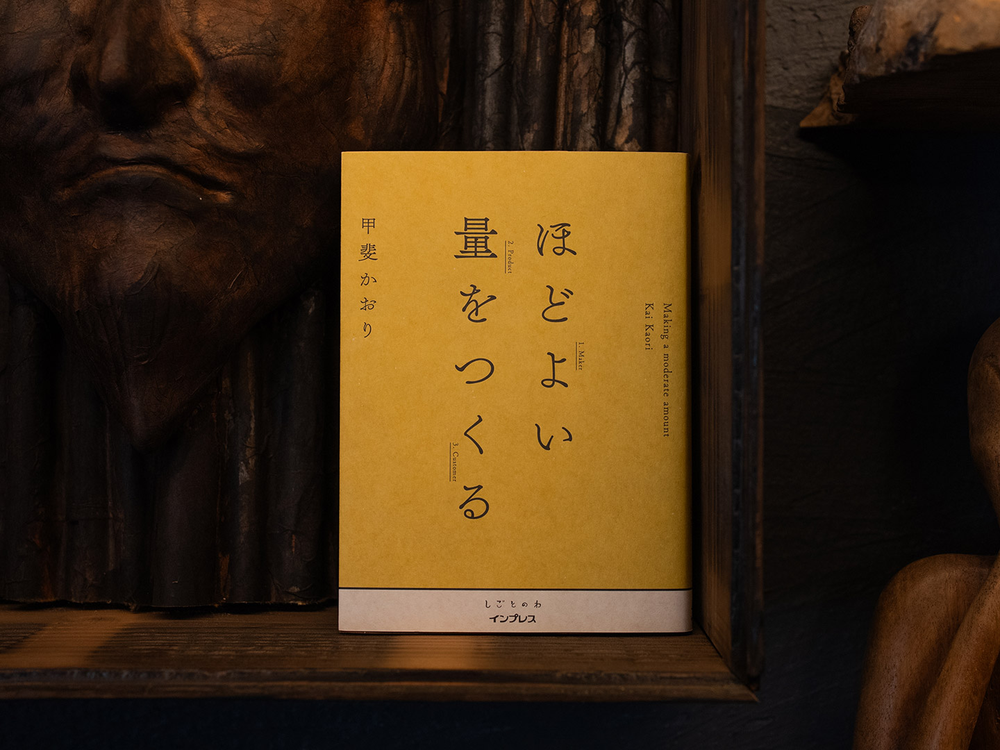 木でできたお面の前に、甲斐かおり 『ほどよい量をつくる』の本が立てかけてある