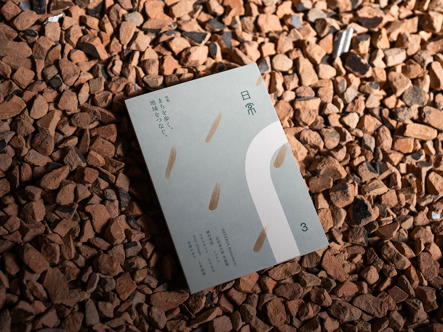 赤茶色の石州瓦の砂利での上に置かれた、『日常 第3号』の本