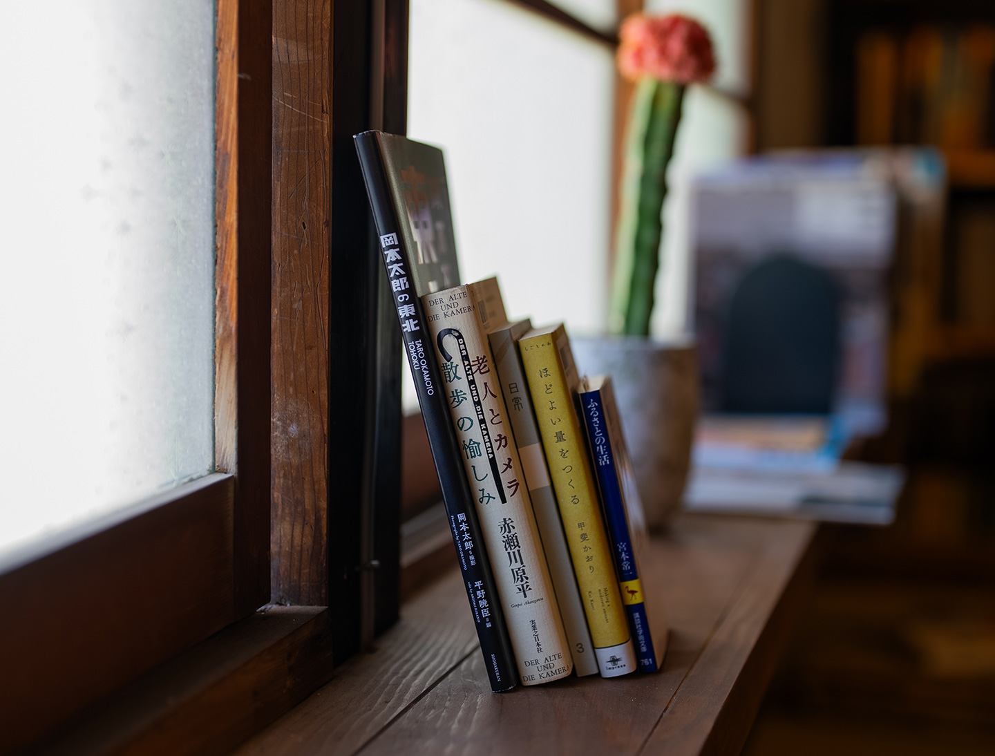 木の窓辺に、5冊の本が背表紙を向けて立てかけてある