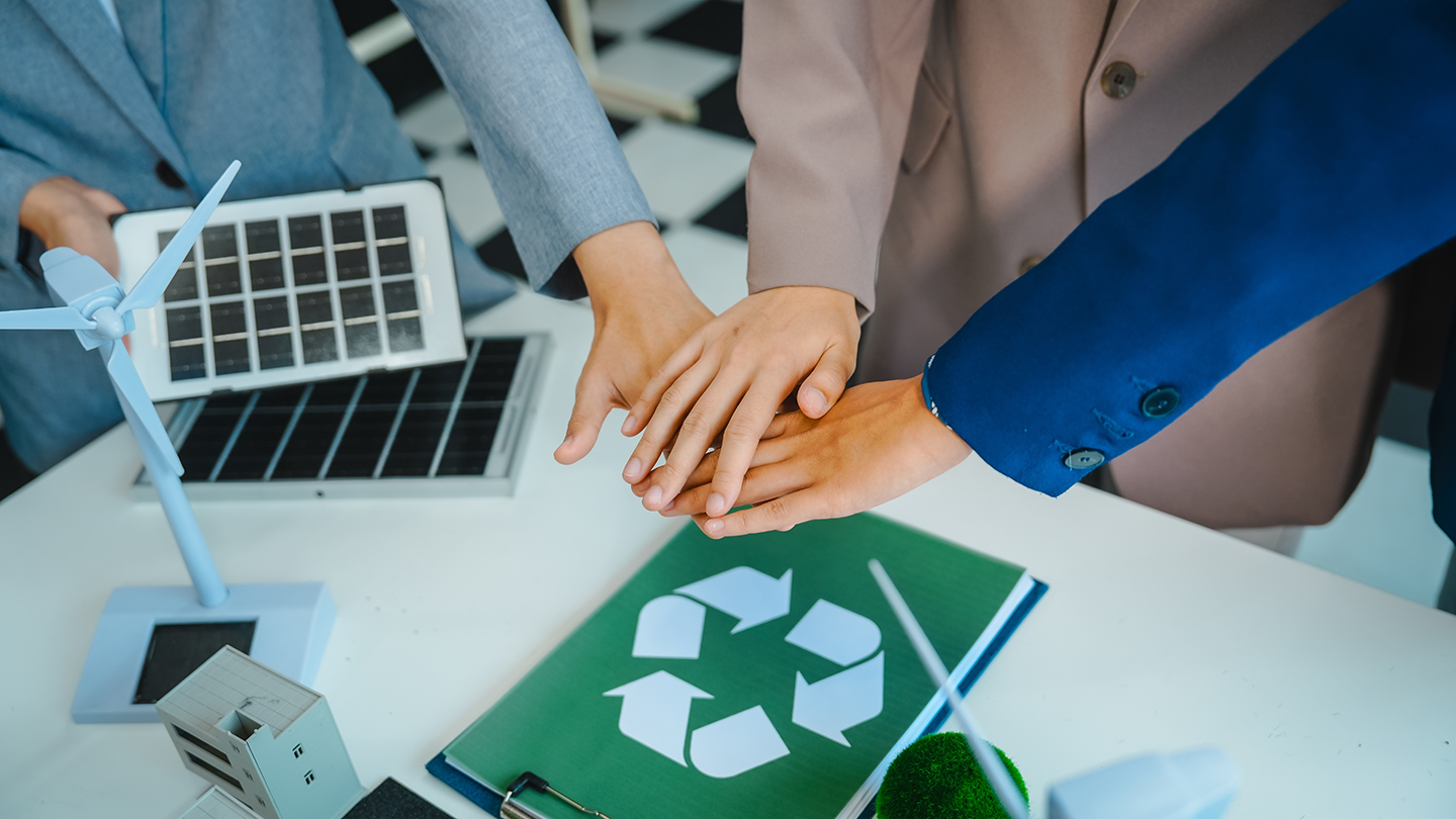 スーツを着た3人がソーラーパネルや風車などのアイテムの上に手をかざす様子